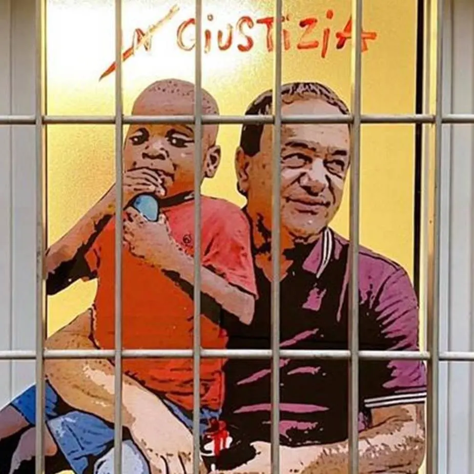 Lucano dietro le sbarre con un piccolo migrante in braccio: la nuova opera di TvBoy