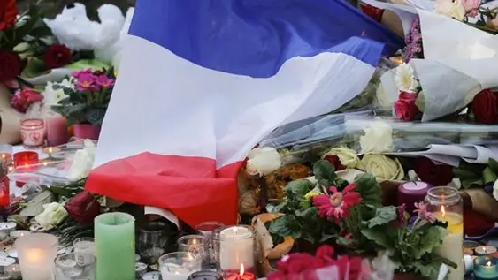 epa05026829 A french flag and flowers are placed at a memorial set near the Bataclan concert venue in Paris, France, 15 November 2015. More than 120 people have been killed in a series of attacks in Paris on 13 November, according to French officials. Eight assailants were killed, seven when they detonated their explosive belts, and one when he was shot by officers, police said. French President Francois Hollande says that the attacks in Paris were an \\'act of war\\' carried out by the Islamic State extremist group. EPA/JULIEN WARNAND , EPA