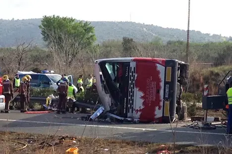 Emergency services personnel stand at the scene of a bus accident crashed on the AP7 highway that links Spain with France along the Mediterranean coast near Freginals halfway between Valencia and Barcelona early Sunday, March 20, 2016. The bus was reportedly hired out to carry students to and from a fireworks festival in Valencia and was on the return leg of its journey when the accident happened. (AP Photo) , AP