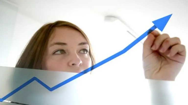 business woman drawing a graph on a glass window in an office - focus is on graph