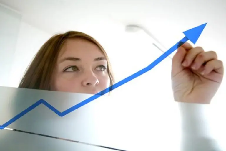 business woman drawing a graph on a glass window in an office - focus is on graph