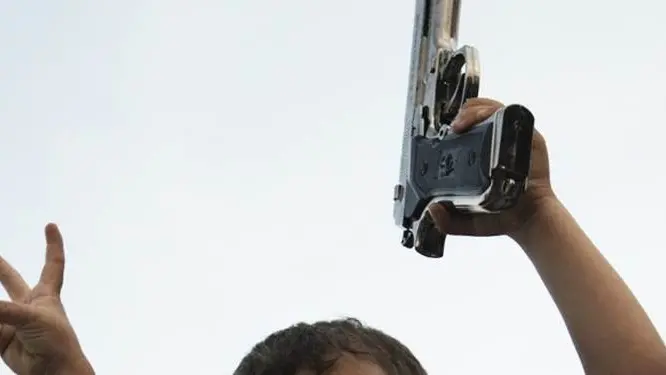 A Libyan child holds a pistol as he sits on his father\\'s shoulders at the site of a blast in the parking lot of the Tibesti hotel, used by rebel leaders, diplomats and journalists, in the eastern rebel stronghold of Benghazi on June 1, 2011. AFP PHOTO/GIANLUIGI GUERCIA (Photo credit should read GIANLUIGI GUERCIA/AFP/Getty Images) , AFP/Getty Images