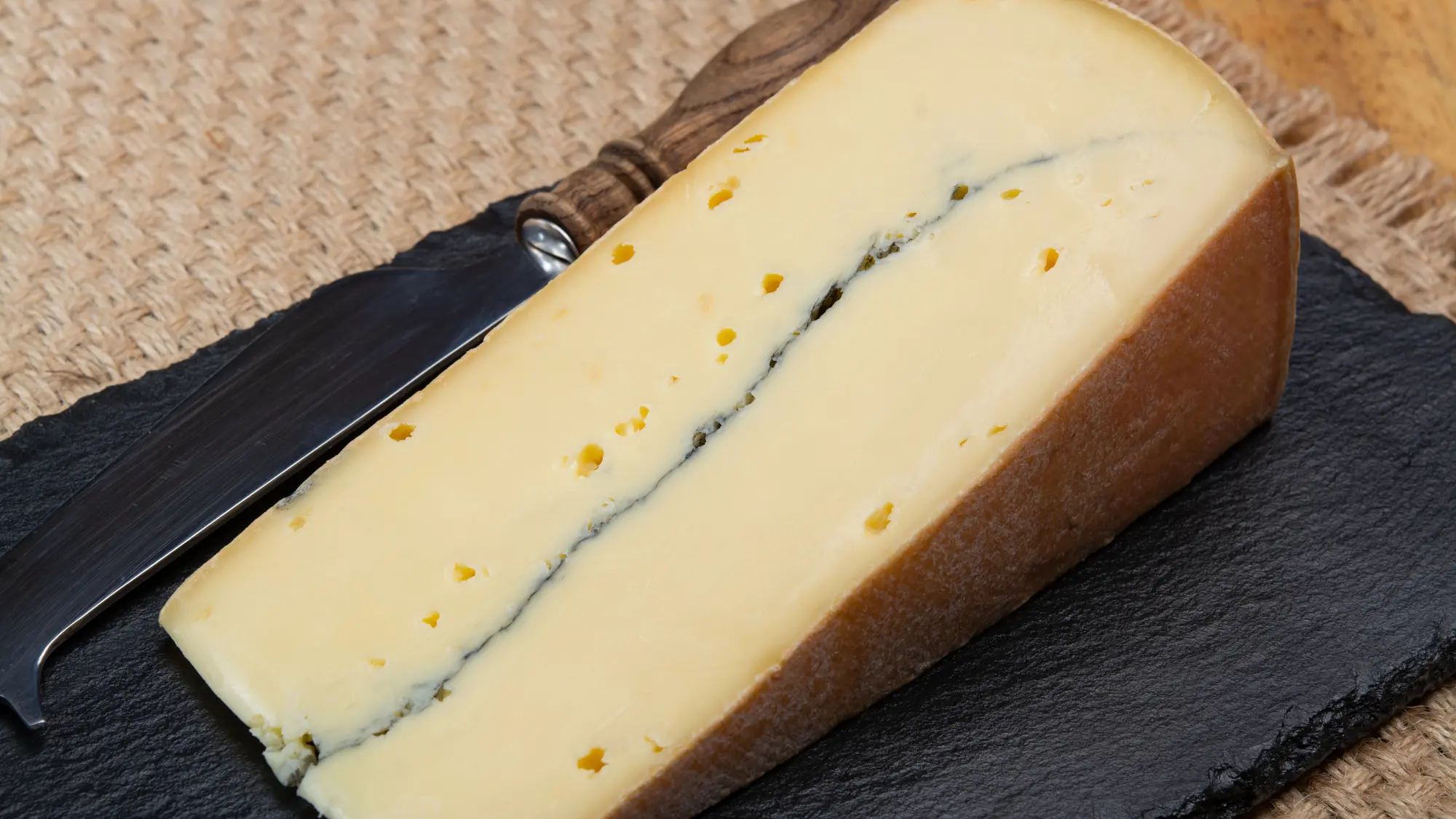 Cheese collection, French Morbier semi-soft cow milk cheese with black mold layer close up