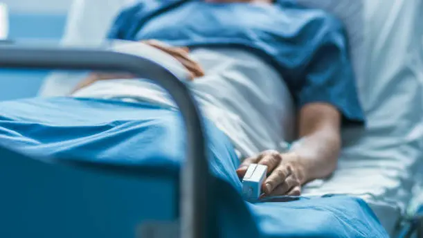 In the Hospital Sick Male Patient Sleeps on the Bed. Heart Rate Monitor Equipment is on His Finger. , Getty Images