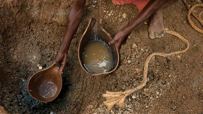 Women scratching for water from the sand of the once full Arayo River. , LYNN JOHNSON/National Geographic Creative