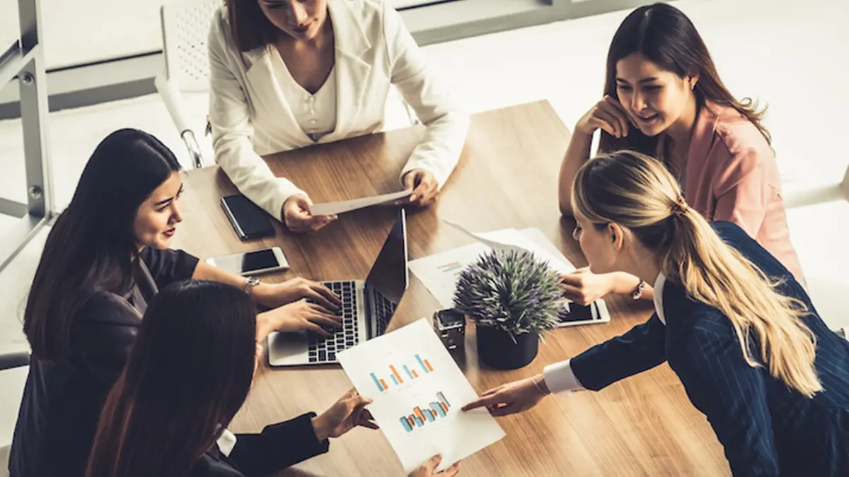 Businesswoman in group meeting discussion with other businesswomen colleagues in modern workplace office with laptop computer and documents on table. People corporate business working team concept. , Blue Planet Studio - stock.adobe.com