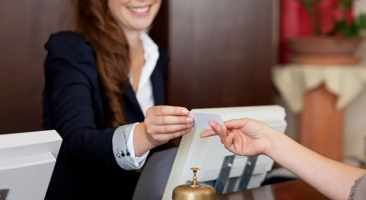 smiling female receptionist passing card to guest