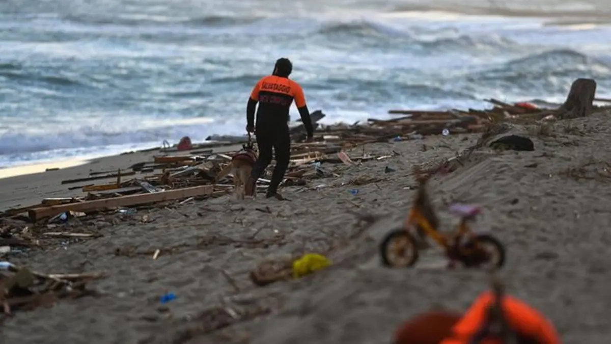A member of the cynophile police and his dog patrol the beach on February 26, 2023 in Steccato di Cutro, south of Crotone, where debris of a shipwreck were washed ashore after a migrants\\' boat sank off Italy\\'s southern Calabria region. - 59 migrants, including a tiny baby, died after their overloaded boat sank early on February 26, 2023 in stormy seas off Italy\\'s southern Calabria region, Italian media and rescue services reported. (Photo by Alessandro SERRANO / AFP) , AFP