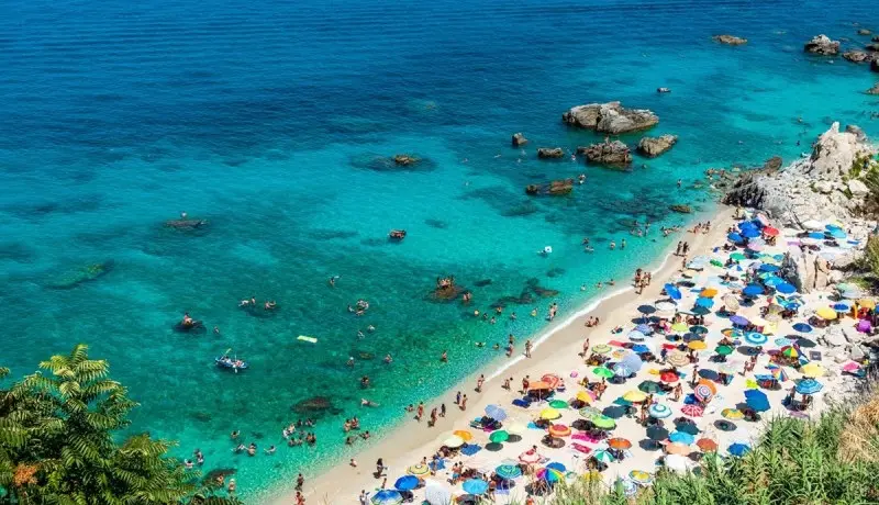 Michelino beach in Parghelia near Tropea during summertime, Calabria, Italy. Sandy beach full of vacationers and colorful umbrellas