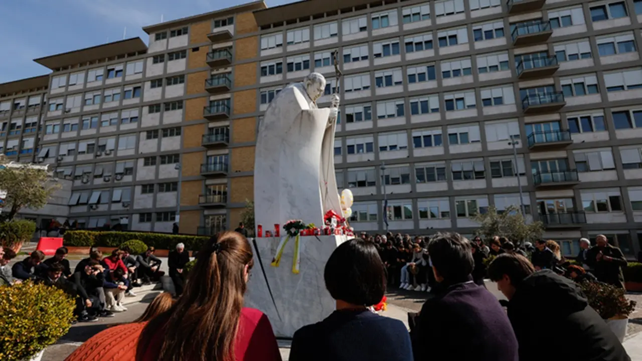 People pray under the statue of late Pope John Paul II outside Agostino Gemelli Hospital where Pope Francis is hospitalized to continues his treatments for bilateral pneumonia, in Rome, Italy, 23 February 2025. ANSA/GIUSEPPE LAMI , ANSA