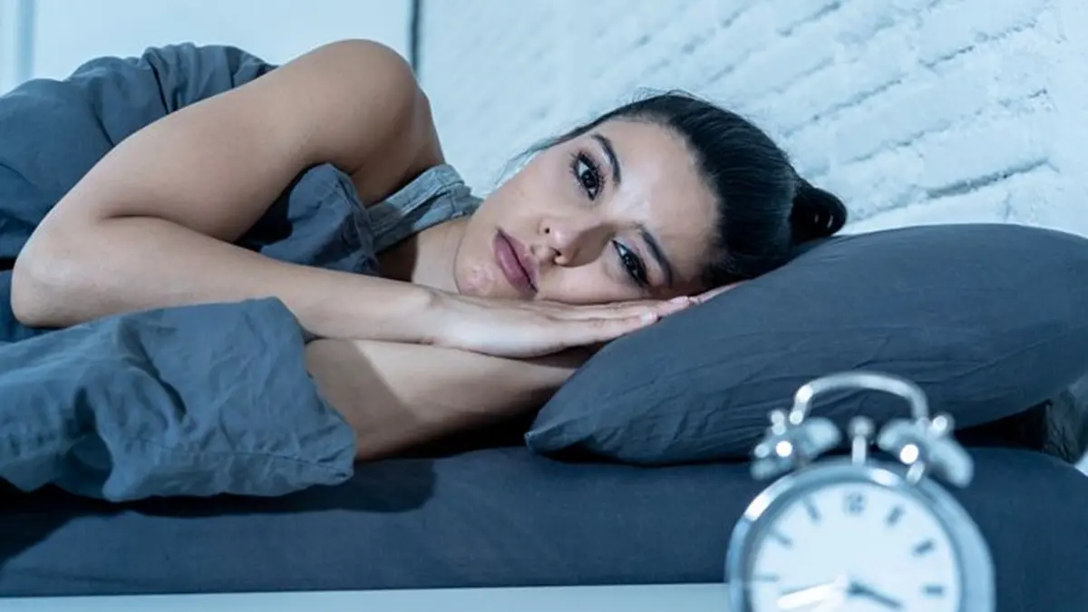 Sleepless and desperate beautiful latin woman awake at night not able to sleep looking at clock suffering from insomnia in sleep disorder concept. , Getty Images/iStockphoto