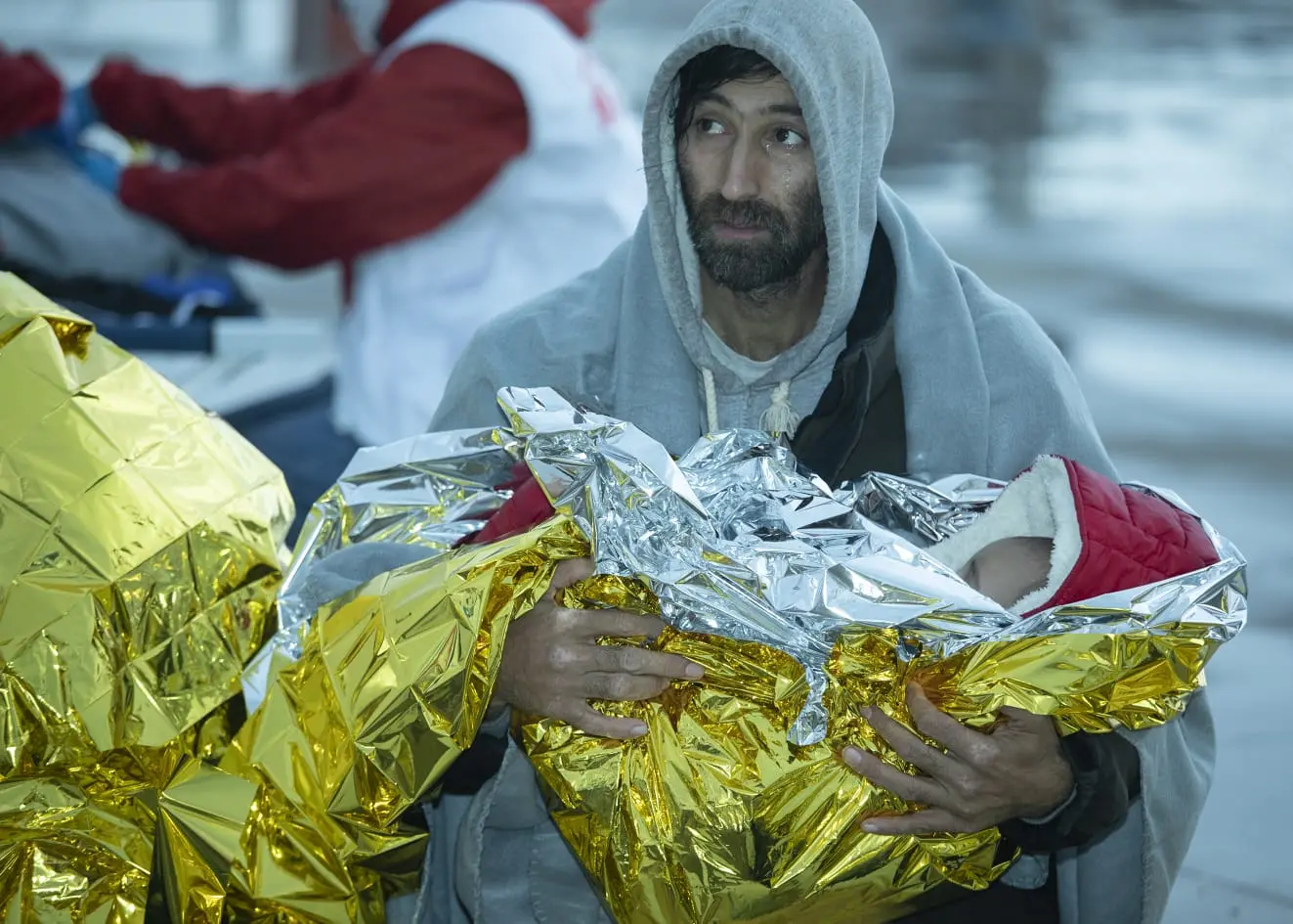 Il migrante che tiene in braccio suo figlio: lo sbarco di Roccella diventa un presepe vivente