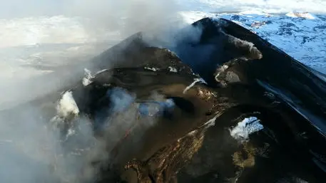 epa08116536 A handout photo made available by Boris Behncke, volcanologist and researcher at National Institute of Geophysics and Volcanology (INGV), shows an aerial view taken from a helicopter of a small lava flow issuing from the cone growing within the Voragine crater at the summit of Mount Etna, Sicily Island, southern Italy, 09 January 2020 (issued 10 January 2020), and cascading into the nearby Bocca Nuova crater (at lower left). Etna is one of the most active volcanoes in the world. EPA/BORIS BEHNCKE/INGV-OSSERVATORIO ETNEO HANDOUT -- MANDATORY CREDIT: BORIS BEHNCKE/INGV-OSSERVATORIO ETNEO -- HANDOUT EDITORIAL USE ONLY/NO SALES , EPA