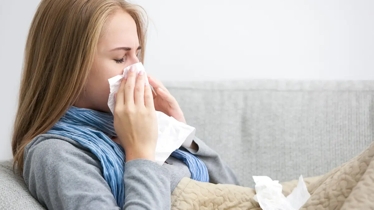 Portrait of a young woman sneezing in to tissue , Shutterstock