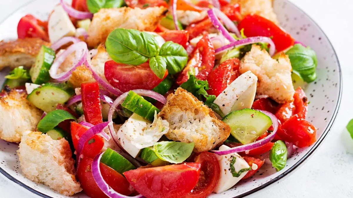 Traditional italian tomato salad panzanella with mozzarella, capers, red onion and croutons. Summer salad.