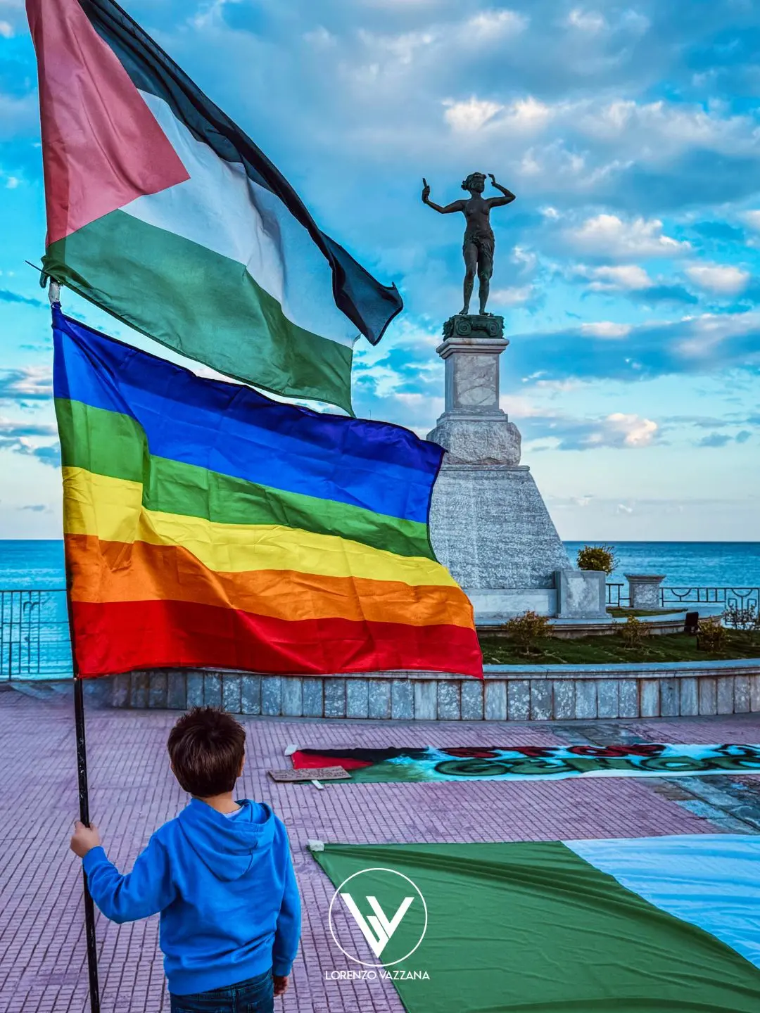 LA FOTO DEL GIORNO | Due bandiere, una voce: il grido di pace di un bambino a Locri