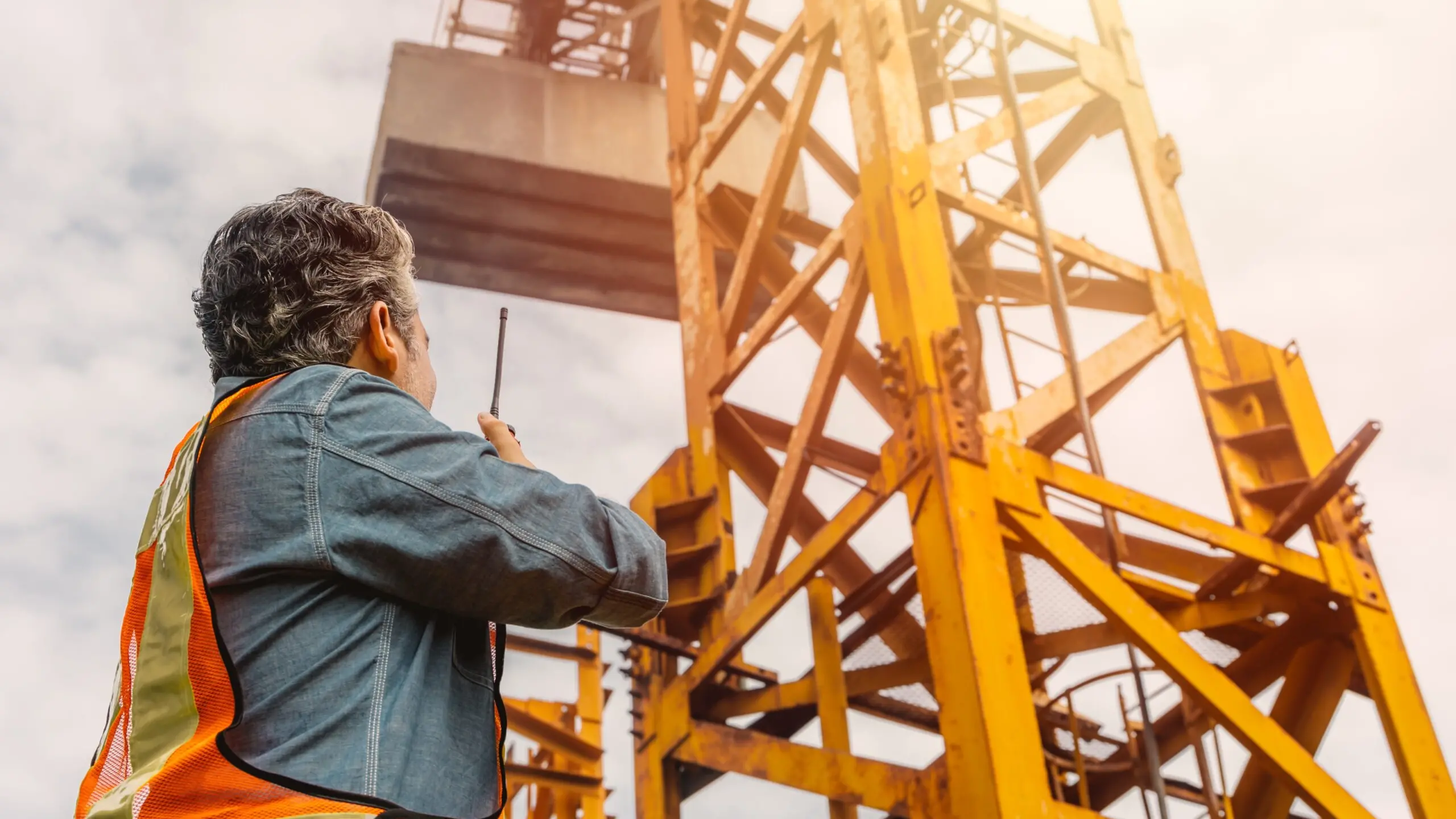 Construction engineer worker construction site radio control operation. Foreman operate tower crane working order by walkie talkie. , Shutterstock