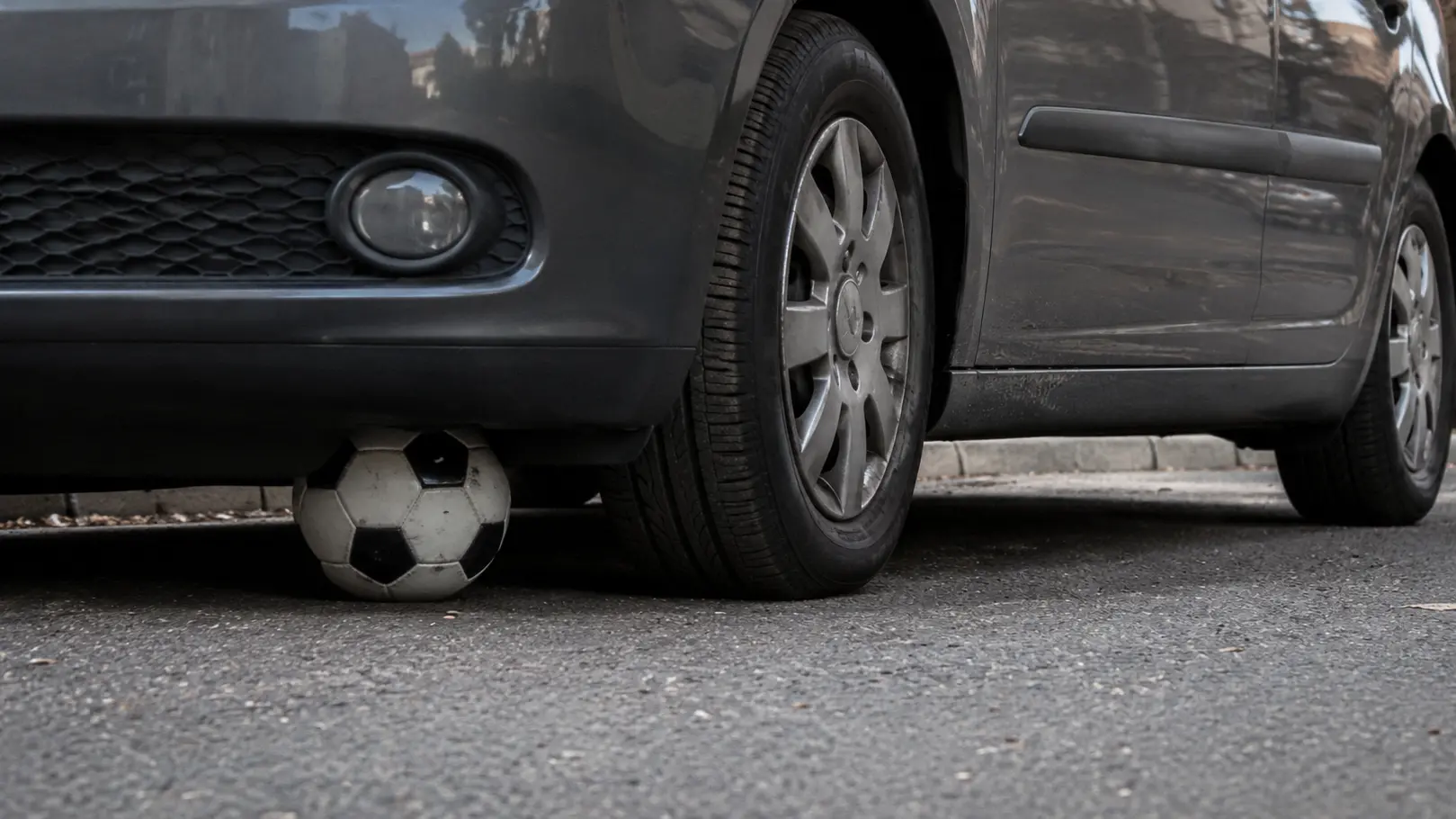 <p>Pallone finisce sotto un'auto (AI)</p>\\n