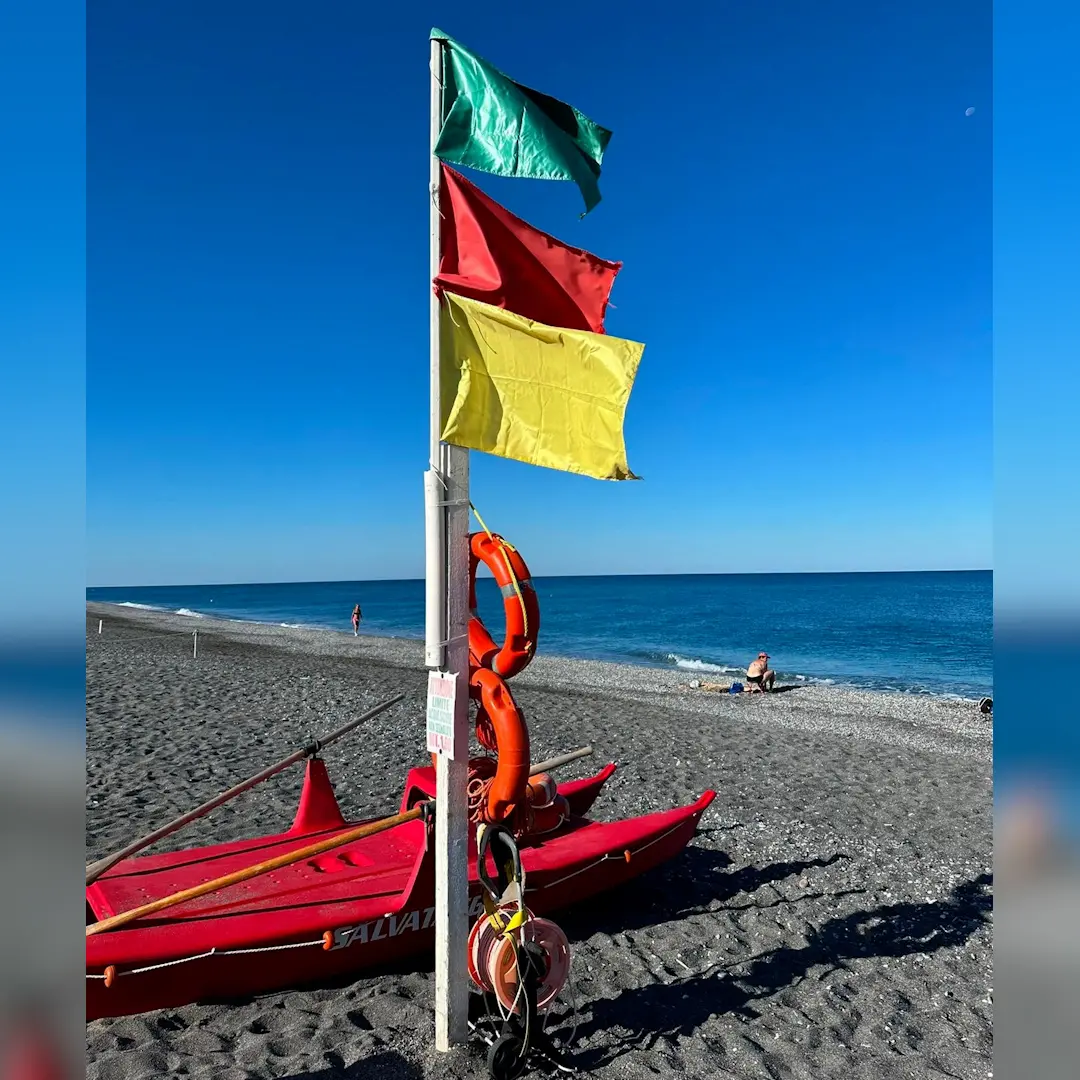 <p>Scalea, sulla spiaggia issate le bandiere verde, rossa e gialla in ricordo del giovane camerunense trovato morto in mare</p>